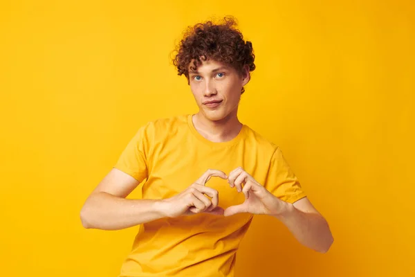 Fiatal göndör hajú férfi sárga póló divat kéz gesztusok elszigetelt háttér változatlan — Stock Fotó