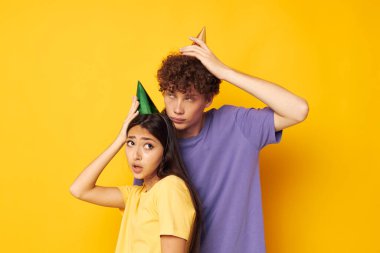 Bir erkek ve bir kız sarı arka planda sarılıyorlar.