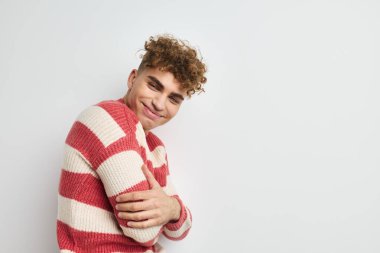 Çizgili kazaklı çekici bir adam. Yaşam tarzını değiştirmemiş şekilde poz veriyor.