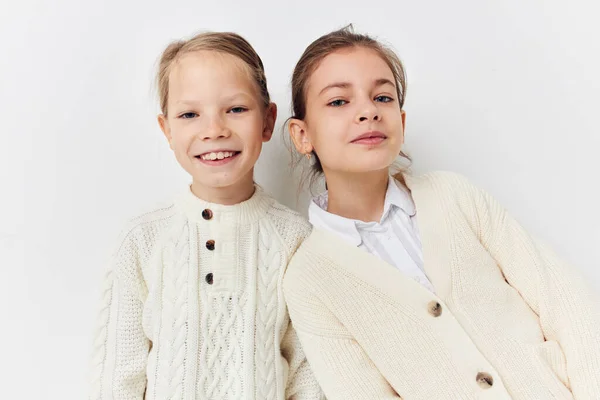 Two little girls in sweaters posing childhood light background — Stock fotografie