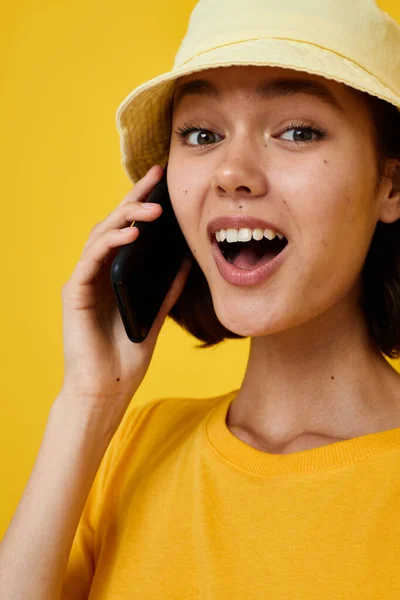 Ελκυστική γυναίκα σε ένα κίτρινο καπέλο Νεανικό στυλ casual μιλώντας στο τηλέφωνο απομονωμένο φόντο — Φωτογραφία Αρχείου