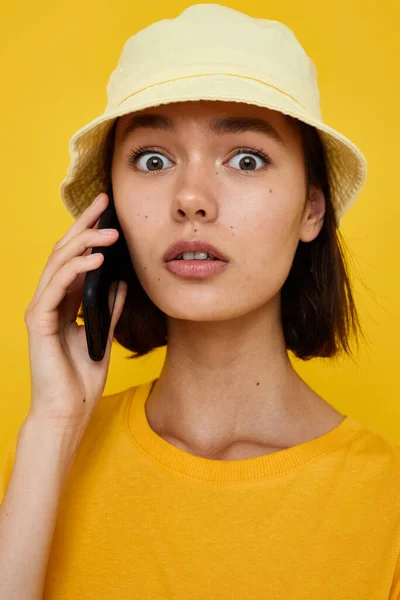 Attraente donna in un cappello giallo stile giovanile casual parlando sul telefono sfondo isolato — Foto Stock