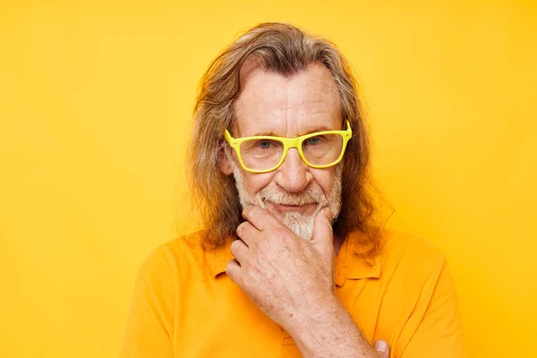 Elderly man in yellow glasses with a gray beard emotions yellow background — Photo