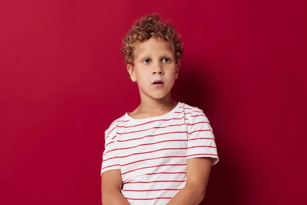 Fröhlicher Junge im gestreiften T-Shirt lächelt vor rotem Hintergrund — Stockfoto