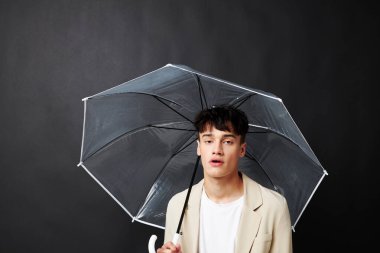 Şeffaf şemsiye koruması olan çekici bir adam.