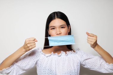 Çekici Asyalı genç kadın tıbbi maske koruması. Geçmişi değiştirilmemiş.