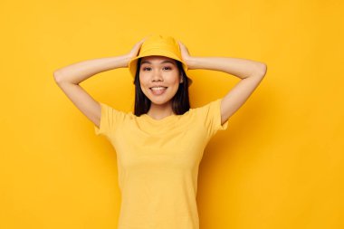 Sarı şapkalı, çekici genç Asyalı kadın duygularını sarı arka planda belli ediyor.