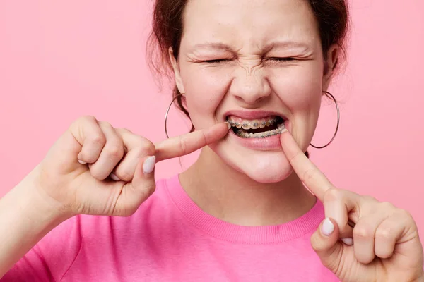 Frau in rosa T-Shirt Hosenträger posiert rosa Hintergrund — Stockfoto