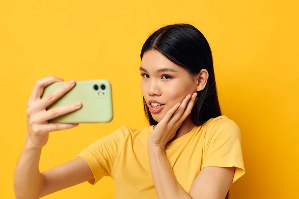 노란 티셔츠를 입고 단색 사진을 찍은 전화를 보고 있는 아시아의 모습을 한 여성 — 스톡 사진