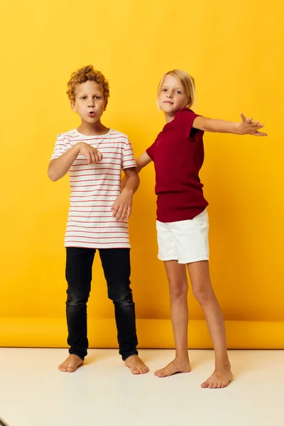 Мальчик и девочка стоят бок о бок, создавая детские эмоции на изолированном фоне — стоковое фото