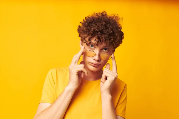 Młody kręcone włosy człowiek noszenie stylowe okulary żółty t-shirt pozowanie monochromatyczne strzał — Zdjęcie stockowe