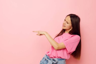 Pembe tişörtlü iyimser genç bir kadın. Sıradan giysiler, izole edilmiş bir arka plan.