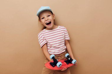 Güzel genç kız kaykay elinde bebek kıyafetleri poz veriyor izole edilmiş eğlenceli bir arka plan