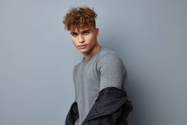 Gri kazaklı yakışıklı genç adam. Moda stüdyosu izole edilmiş.