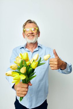 Yaşlı bir adam bir buket çiçek ve hediye olarak hafif bir arka plan.