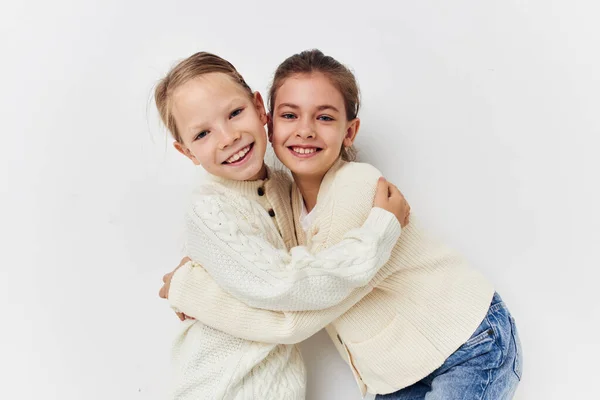 Two little girls in sweaters posing childhood light background — Stock fotografie