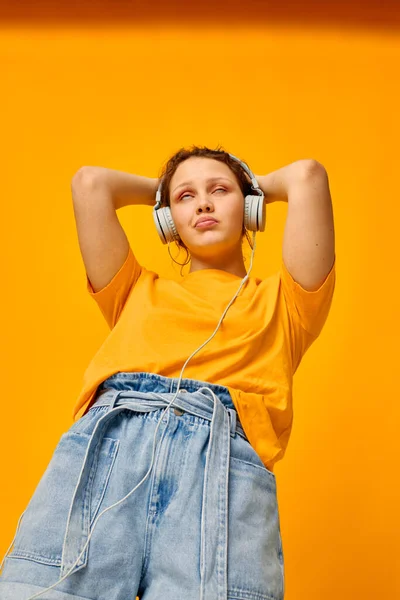 Alegre mujer amarillo camiseta auriculares entretenimiento música divertido amarillo fondo inalterado — Foto de Stock