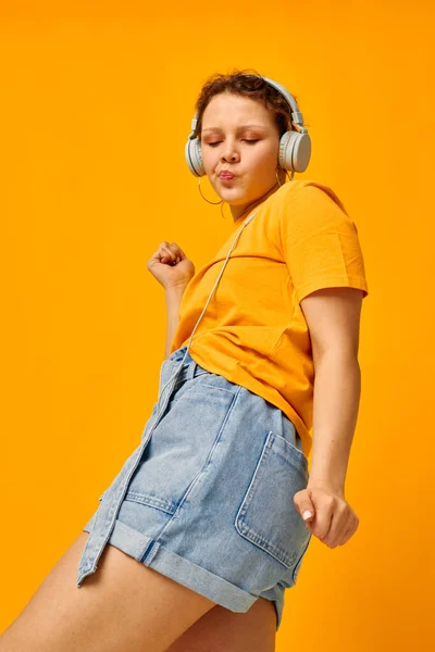 Όμορφη κοπέλα καλοκαίρι στυλ ακουστικά χορό κίτρινο φόντο αμετάβλητη — Φωτογραφία Αρχείου
