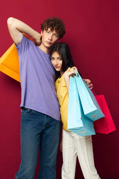 Schattig jong paar kleurrijke tassen winkelen leuk rood achtergrond ongewijzigd — Stockfoto
