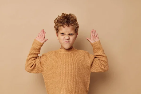 베이지 스웨터를 입은 귀여운 소년은 변하지 않은 재미있는 어린 시절을 연출 한다 — 스톡 사진