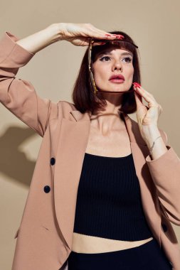 Güneş gözlüklü, kısa saçlı, el hareketleriyle arka planda olan güzel bir kadın.