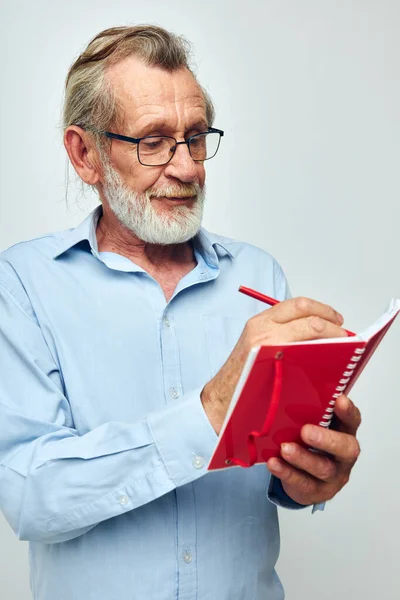 Portret oudere man met rode notebook en pen lichte achtergrond — Stockfoto