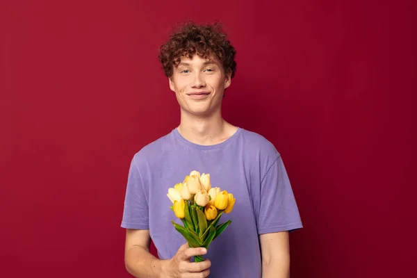 Cute teen holding a yellow bouquet of flowers purple t-shirts red background unaltered — ストック写真