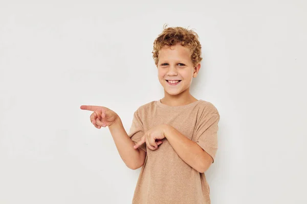 Смешной кудрявый мальчик в белой футболке жестикулирует руками — стоковое фото