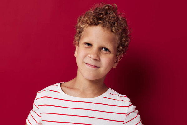 Веселый мальчик в полосатой футболке с улыбкой на красном фоне