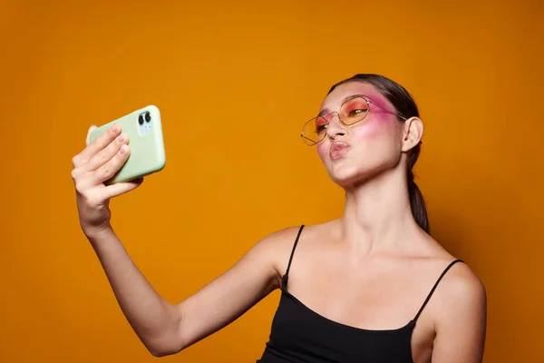 Retrato de bela jovem mulher sorrir brilhante rosa maquiagem emoções cosméticos smartphone selfie amarelo fundo inalterado — Fotografia de Stock
