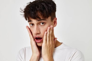 Beyaz tişörtlü, arka planda değişmemiş genç bir adam dövmesi.