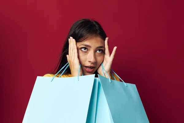 Brunette met pakketten in handen winkelen rode achtergrond — Stockfoto