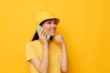 Güzel esmer, telefonda konuşuyor. Moda modasına uygun, değiştirilmemiş bir arka plan.