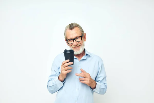 Old man with a black glass in his hands a drink isolated background — Stock fotografie