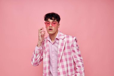 Şık ceketli yakışıklı adam. Kendine güveni ve pembe arka planı değişmemiş moda jestleri.