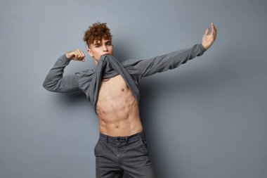 Gri tişörtlü şık bir adam. Moda stüdyosu. Gri arka plan.