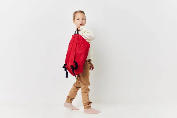 Mutlu gülümseyen kız çocuğunun portresi kırmızı sırt çantası şık kıyafetler ışık arka plan — Stok fotoğraf