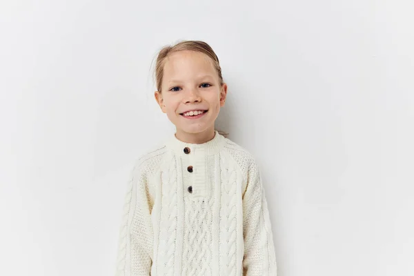 Little girl white sweater hand gestures light background — Foto Stock