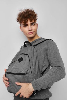 Gri sırt çantalı yakışıklı genç adam izole edilmiş bir arka plan.