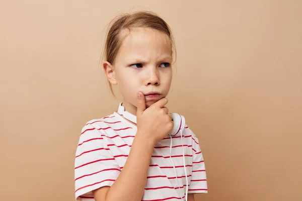 Little girl in striped t-shirt headphones gesture hands beige background — Stockfoto