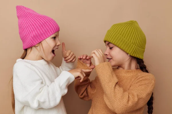 Duas meninas estão de pé ao lado um do outro em chapéus emoções de moda — Fotografia de Stock