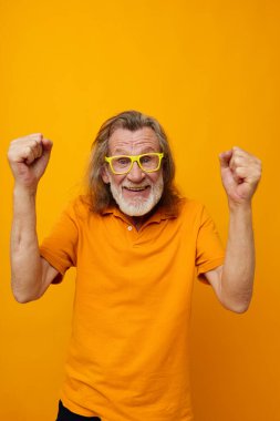 İzole edilmiş arka plan pozu veren sarı tişört ve gözlüklü yaşlı bir adam portresi