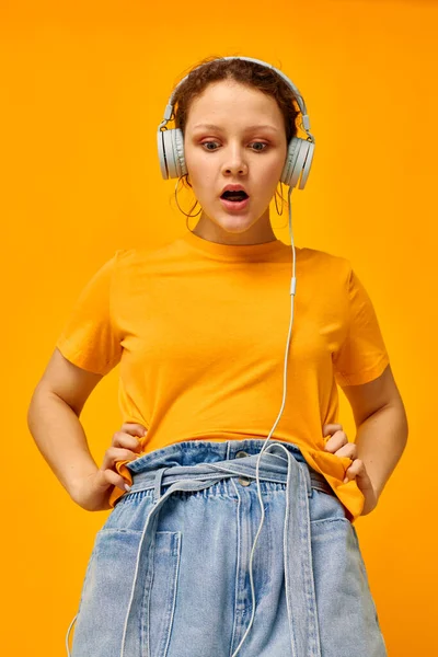 Όμορφη γυναίκα φορώντας ακουστικά denim σορτς close-up συναισθήματα κίτρινο φόντο αναλλοίωτο — Φωτογραφία Αρχείου