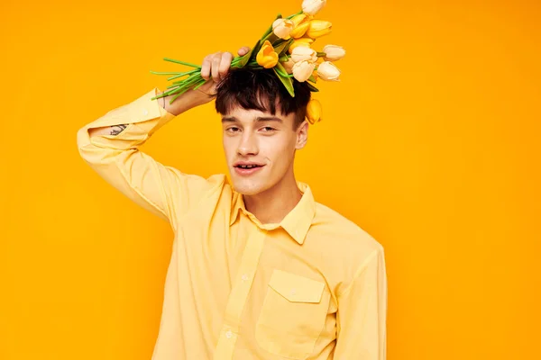 Un joven con un peinado de moda en camisas amarillas con flores de fondo amarillo inalterado — Foto de Stock