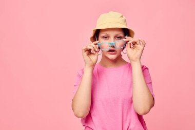 Pembe tişörtlü ve şapkalı genç bir kadın. Pembe arka plan.