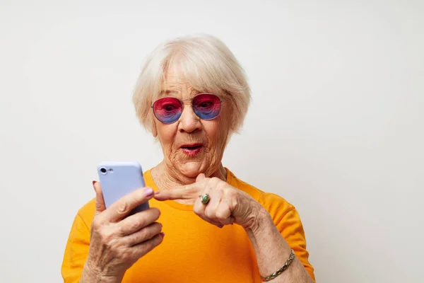 電話で話しているカジュアルなTシャツのサングラスで引退した老婦人の写真クロップドビュー — ストック写真