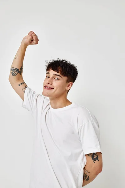Ritratto di un giovane uomo moderno stile giovanile bianco t-shirt tatuaggio sul braccio modello studio — Foto Stock