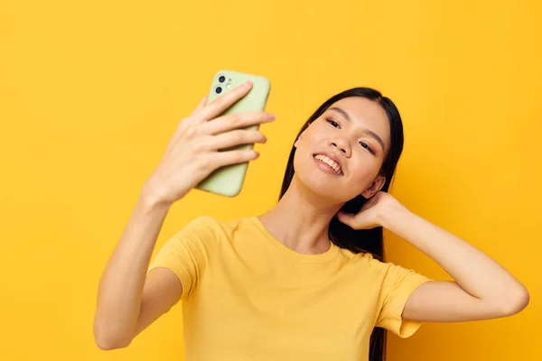 Donna in una t-shirt gialla guardando il telefono posa modello in studio inalterato — Foto Stock