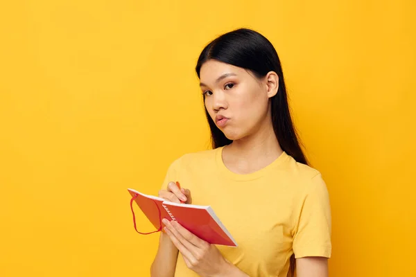 Femme dans un t-shirt jaune carnet rouge formation fond jaune inchangé — Photo