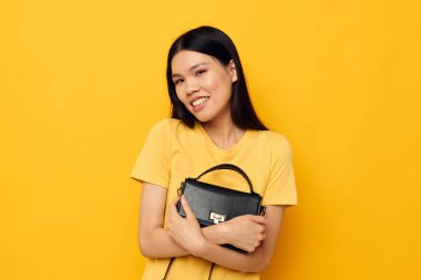 Sarı tişörtlü güzel kadın siyah çantalı poz veren moda.